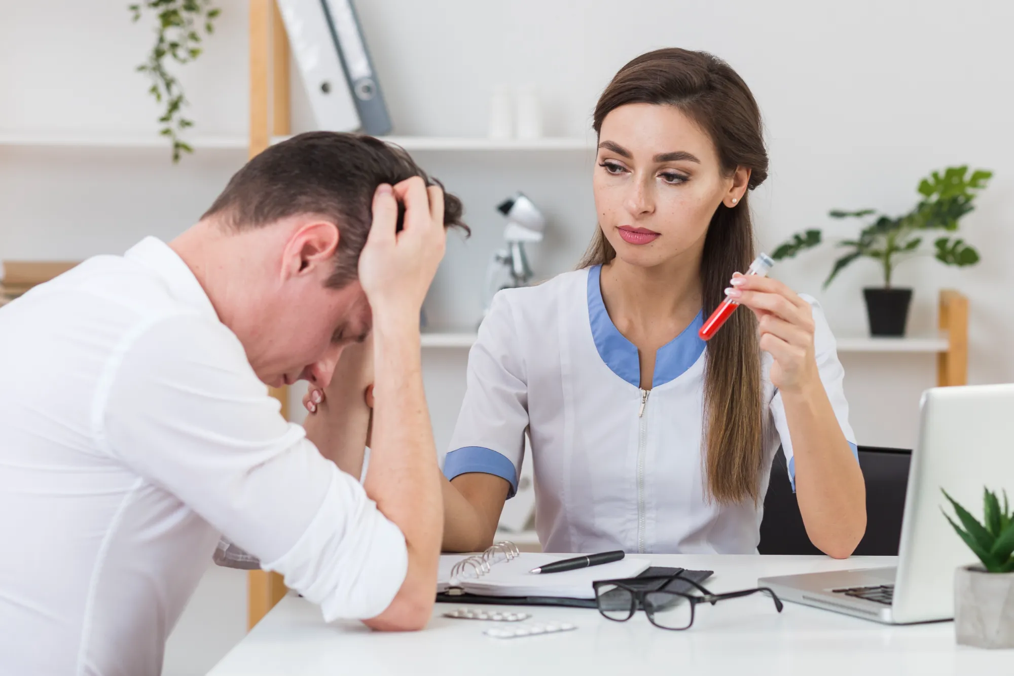 A doctor who appears to be consoling a man regarding a blood sample that she is holding