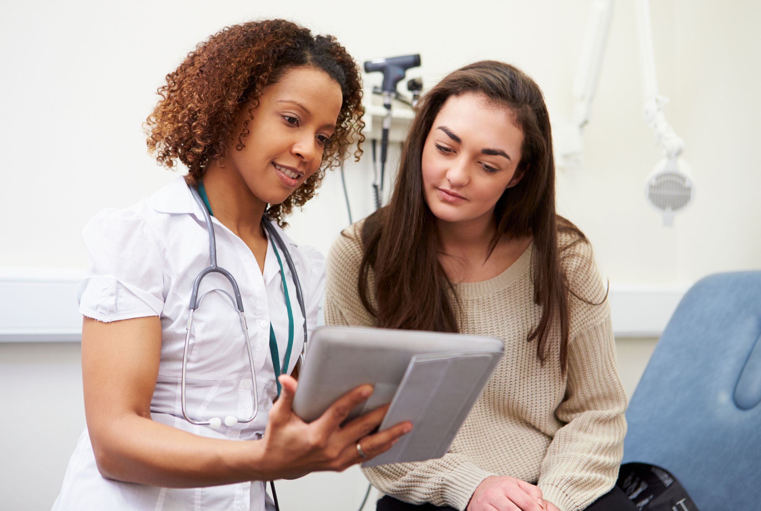 A nurse and woman viewing a chart together in the examination room